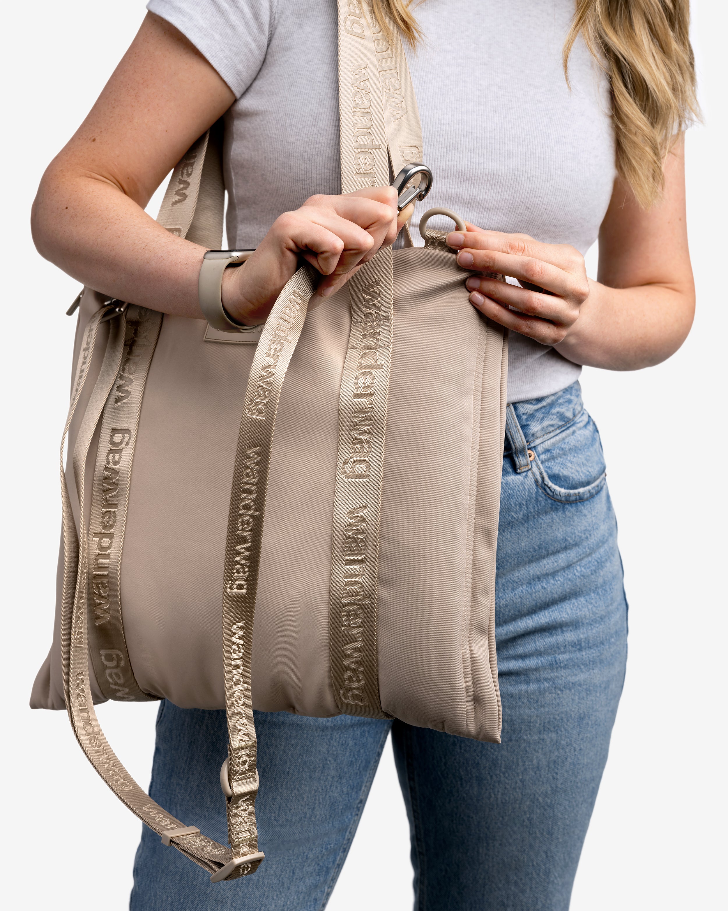 person demonstrating the clipping the cross body strap onto the tote