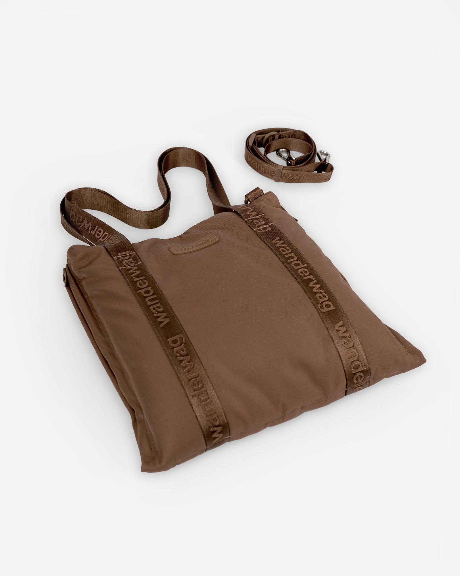 the tote and cross body strap next to it laying flat on a white studio backdrop