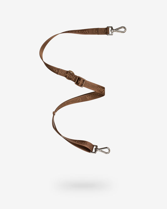 the leash that can be used as a cross body strap for the tote is being displayed on a white back drop