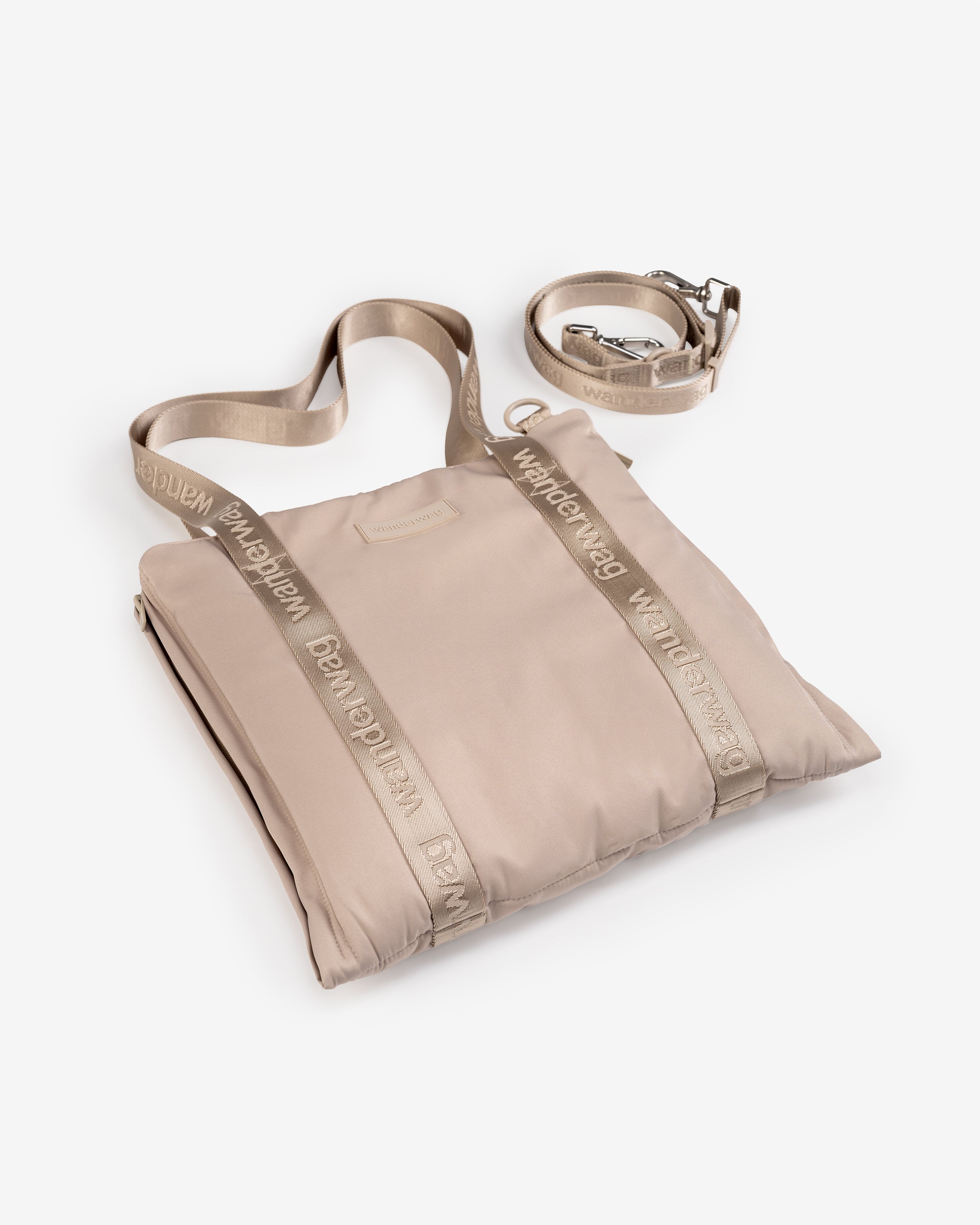 the tote and cross body strap next to it laying flat on a white studio backdrop