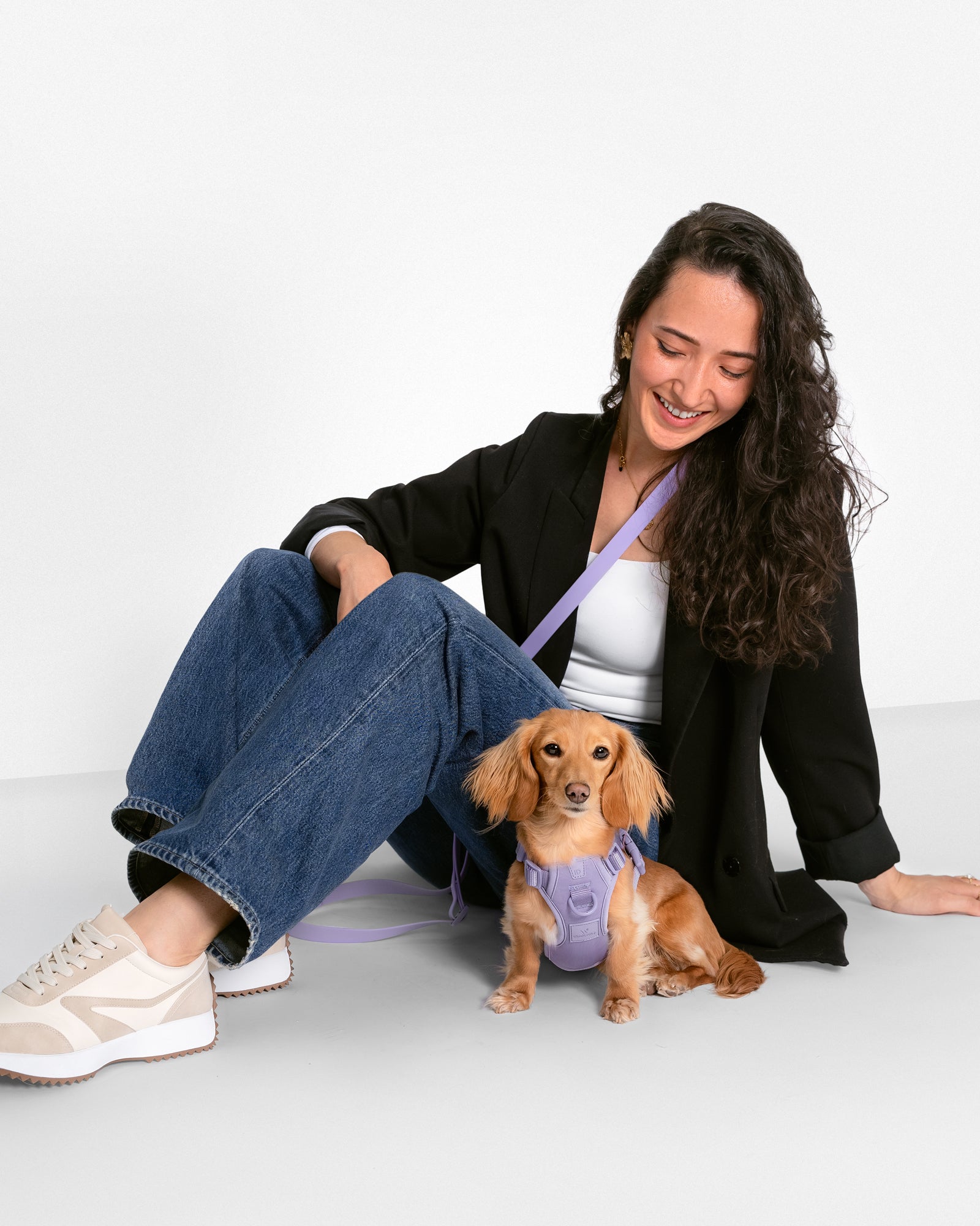 dog wearing harness sitting with a female human sitting next to the dog