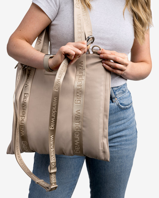 person demonstrating the clipping the cross body strap onto the tote