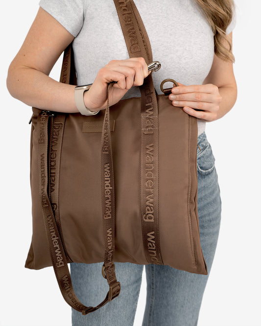 person demonstrating the clipping the cross body strap onto the tote